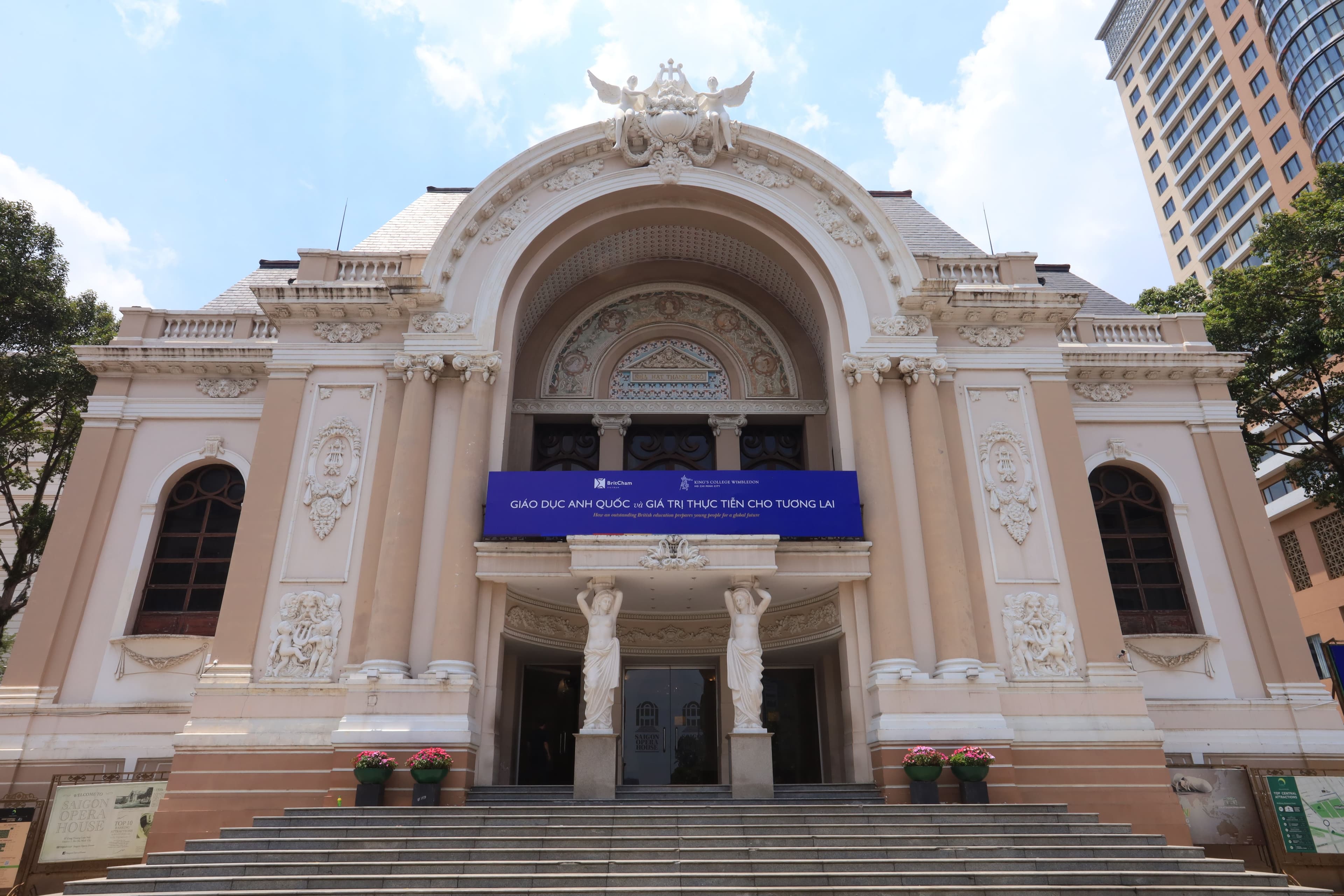 A grand beige neoclassical opera house with an arched entrance and statues.