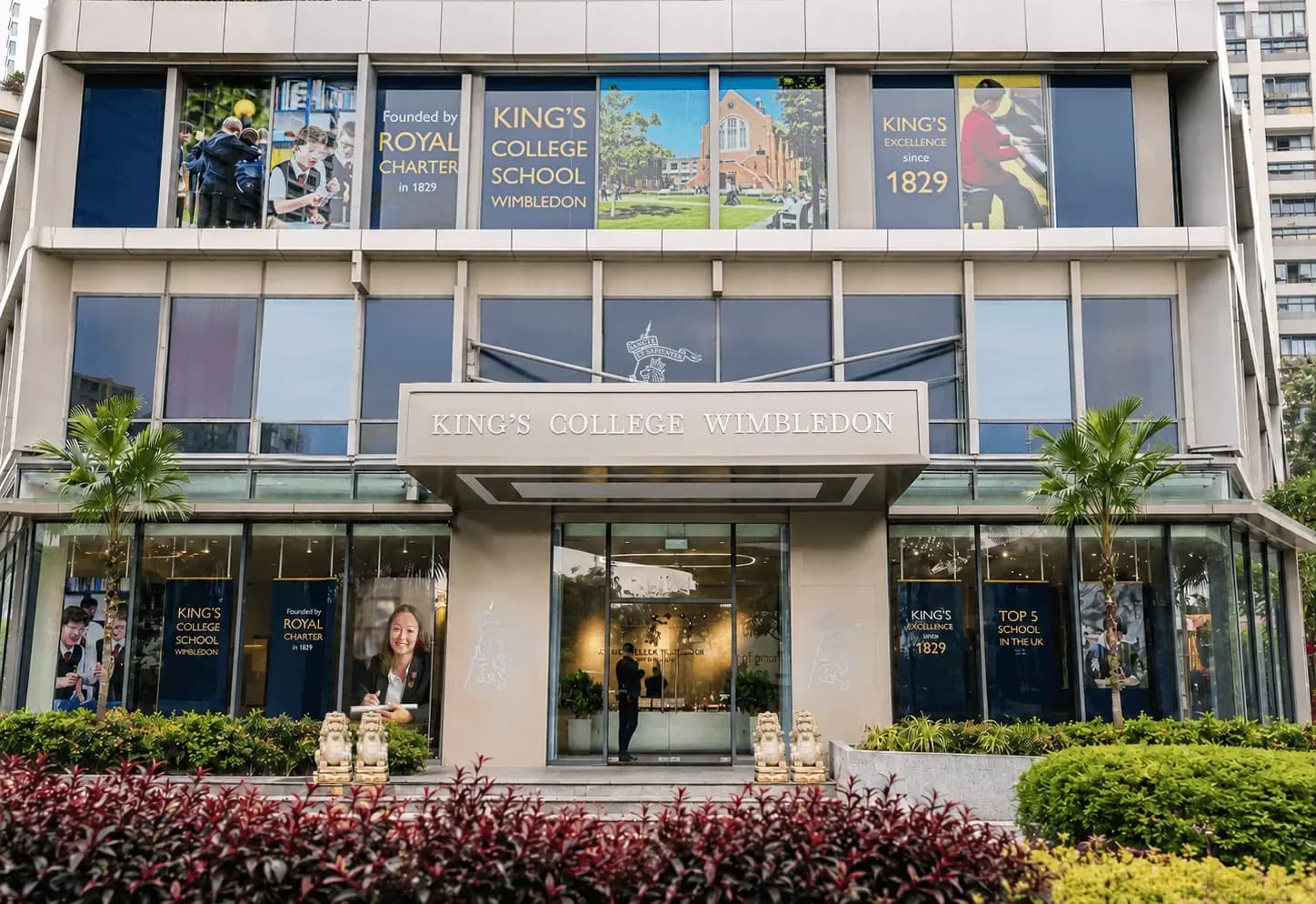 Modern building of King's College School with large windows and promotional banners.